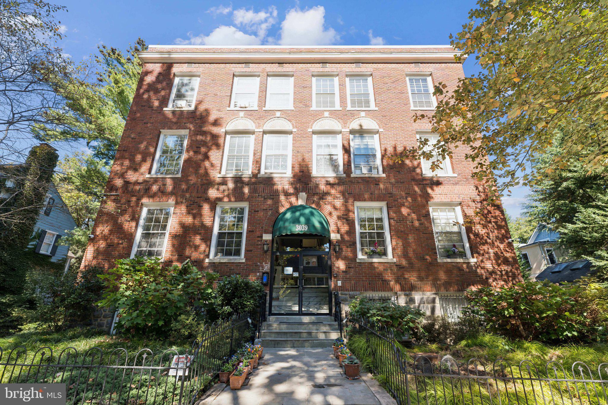 a front view of a multi story residential apartment building with a yard and potted plants