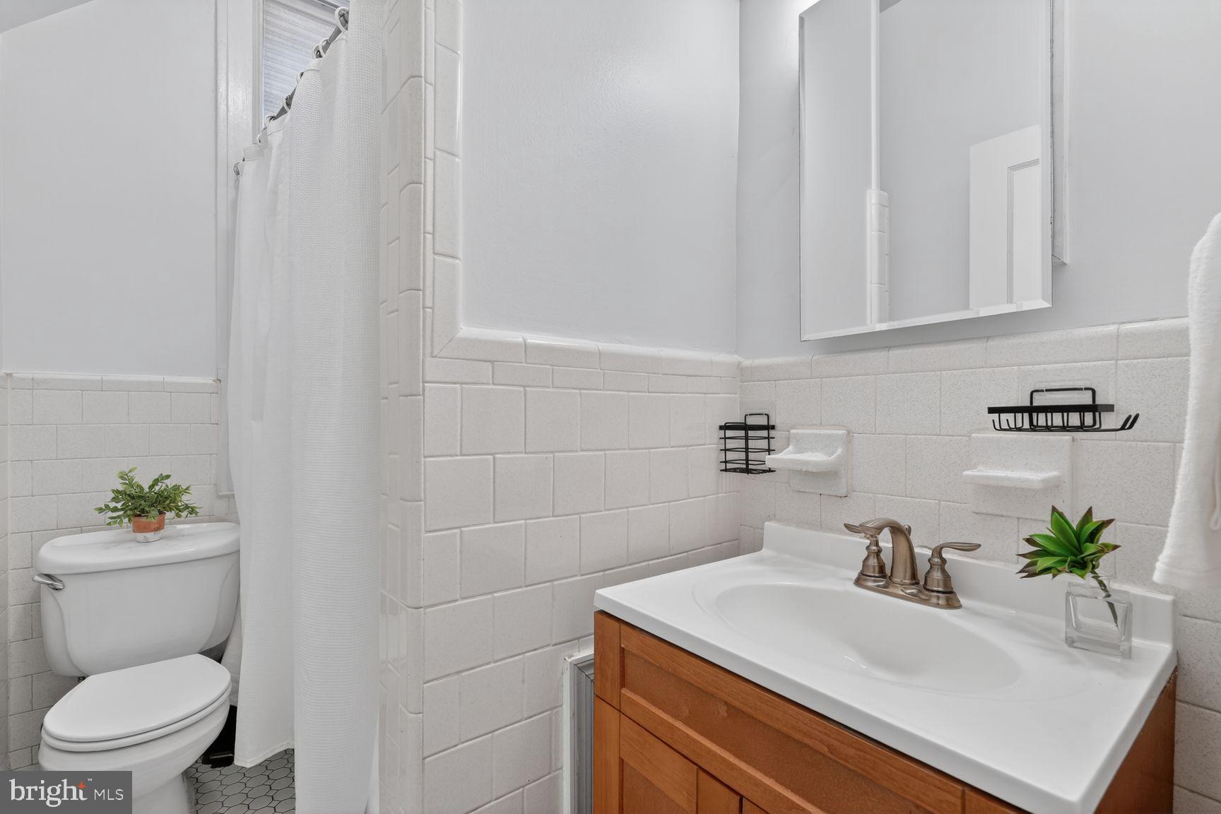 3039 Macomb Street Northwest, Unit 16 Washington, DC 20008 - Photo 14 of 17 a bathroom with a sink a toilet and a mirror
