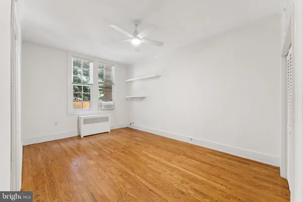 an empty room with wooden floor cabinet and windows