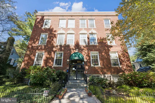 a front view of a multi story residential apartment building with a yard and potted plants