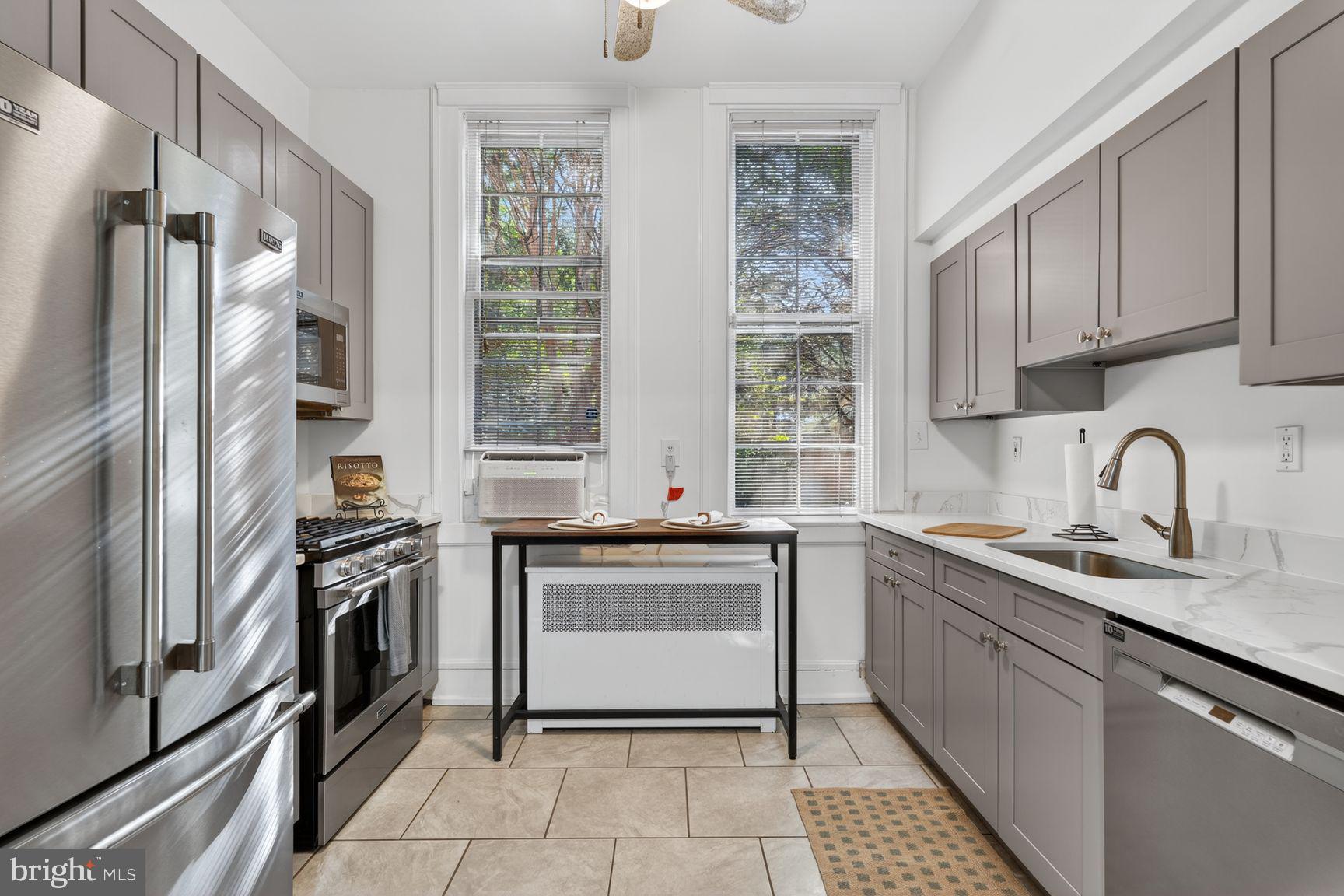 3039 Macomb Street Northwest, Unit 16 Washington, DC 20008 - Photo 8 of 17 a kitchen with stainless steel appliances granite countertop a sink stove and refrigerator