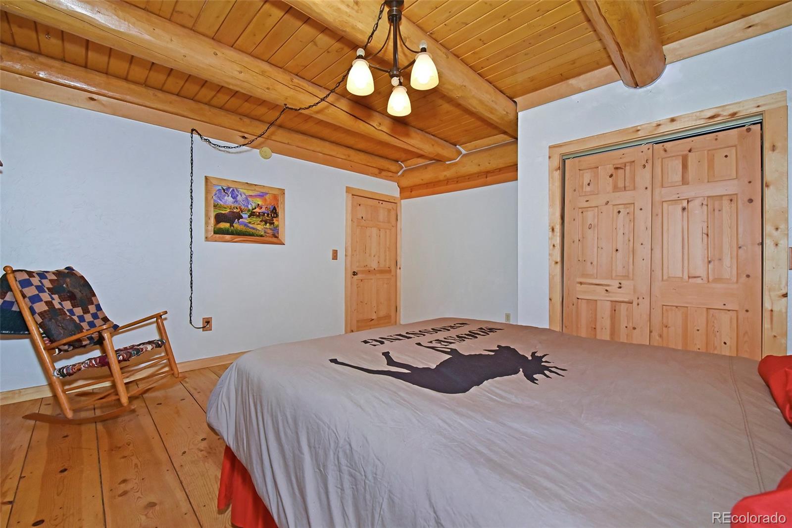 79 Buggy Whip Road Bailey, CO 80421 - Photo 15 of 39 a bedroom with a bed and a chandelier
