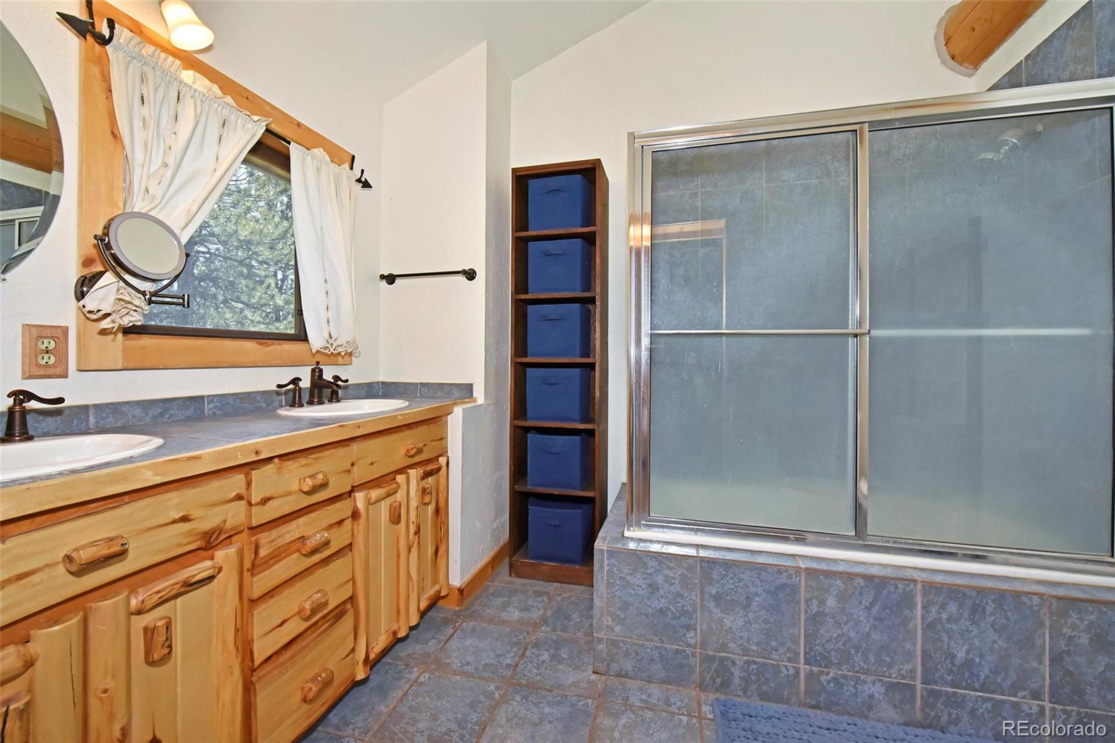79 Buggy Whip Road Bailey, CO 80421 - Photo 23 of 39 a bathroom with a granite countertop sink a mirror and a shower