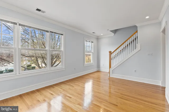 a view of an empty room with wooden floor fireplace and a window
