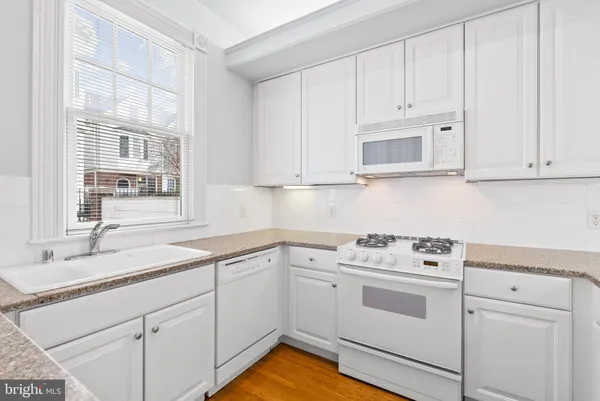 a kitchen with white cabinets and white appliances