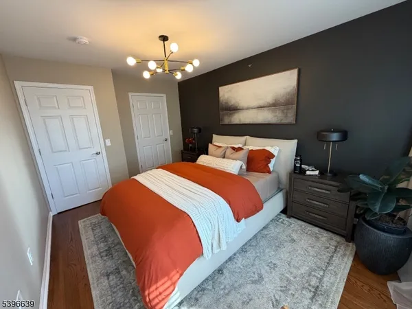 a bedroom with a bed potted plant on dresser and a chandelier