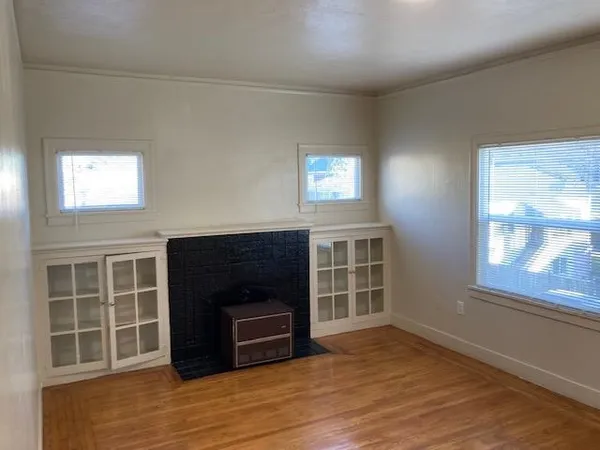 a view of empty room with a fireplace and wooden floor