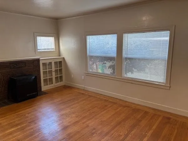 a view of an empty room with a window and wooden floor