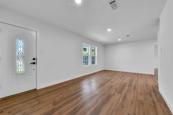 an empty room with wooden floor and windows