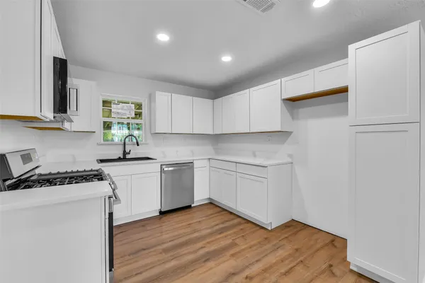 a kitchen with granite countertop a sink cabinets stainless steel appliances and a window