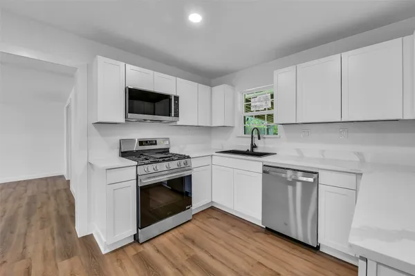 a kitchen with stainless steel appliances granite countertop a stove a sink and a microwave