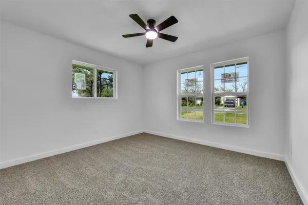a view of an empty room with window and ceiling fan