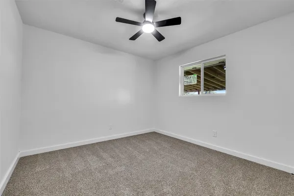 an empty room with ceiling fan and window