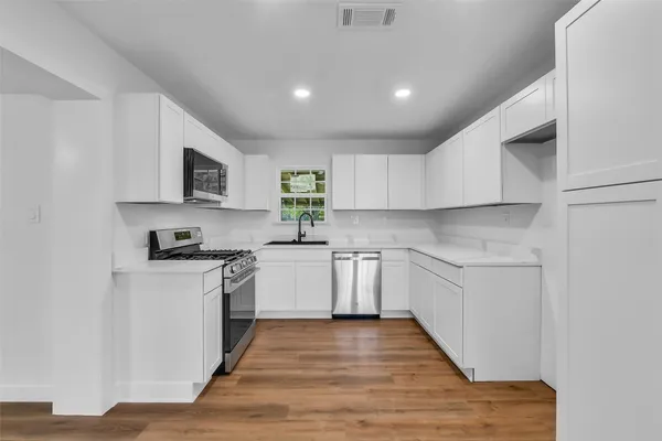 a kitchen with sink a microwave and cabinets