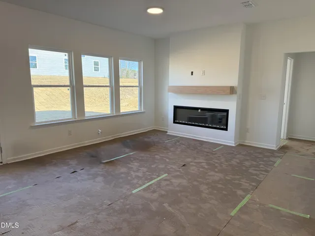 an empty room with windows and fireplace
