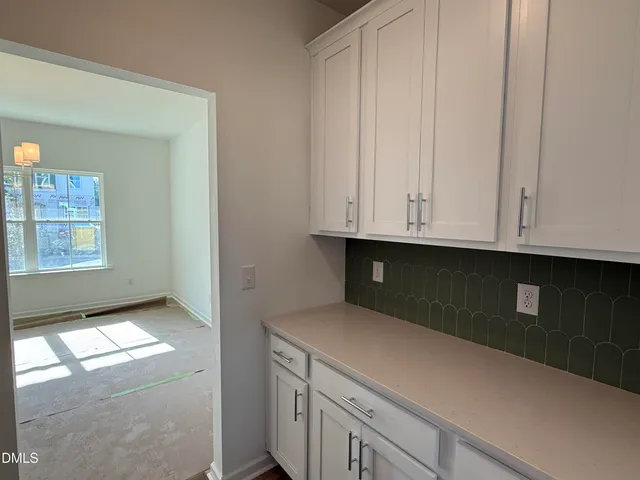 a kitchen with white cabinets and a window