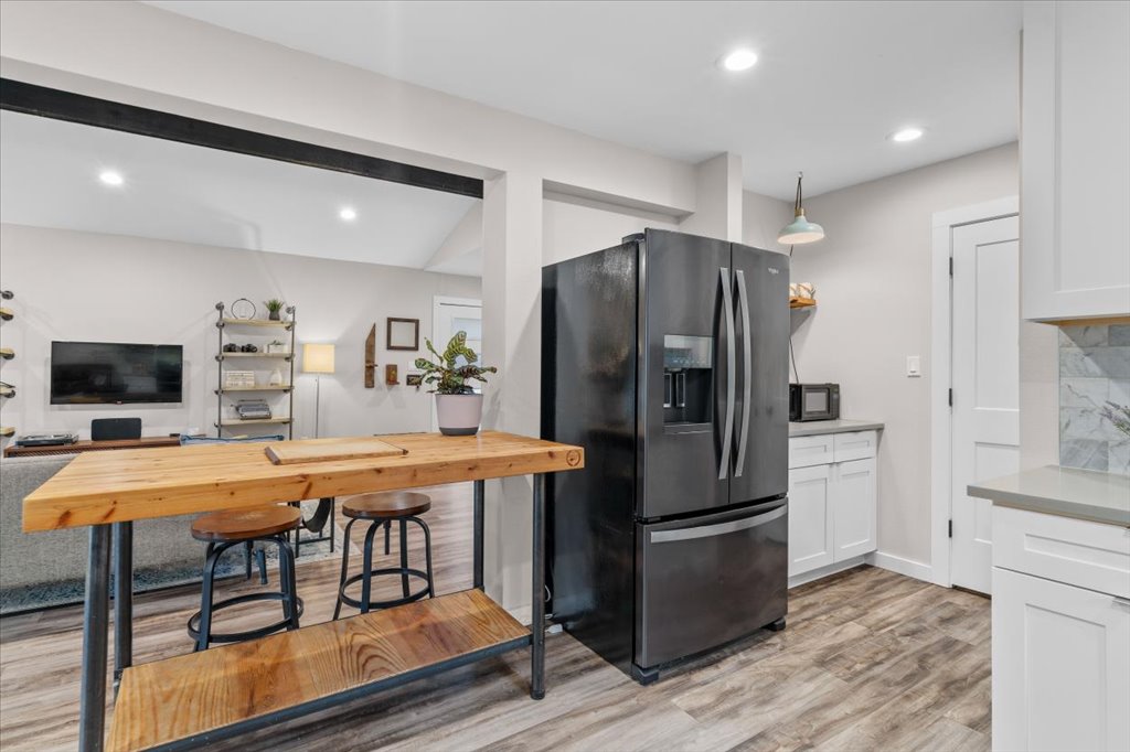 3010 Burleson Road, Unit A Austin, TX 78741 - Photo 12 of 28 Kitchen with black appliances, white cabinets, light wood-style floors, recessed lighting, and light stone counters