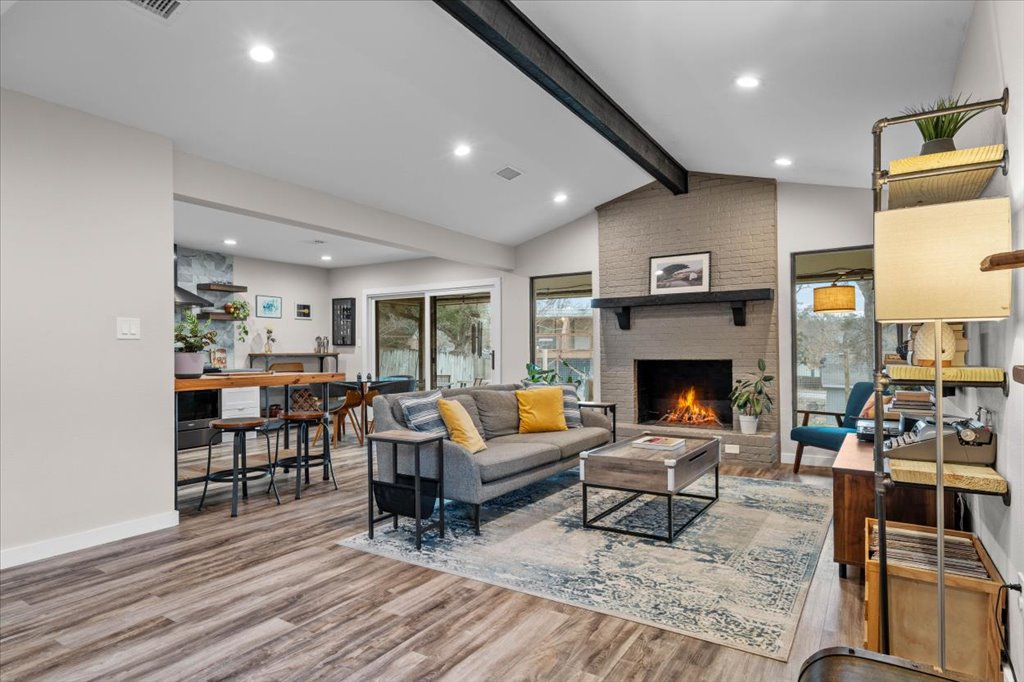 3010 Burleson Road, Unit A Austin, TX 78741 - Photo 2 of 28 Living area with wood finished floors, plenty of natural light, a brick fireplace, lofted ceiling with beams, and recessed lighting