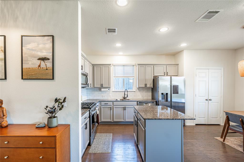 547 Saturnia Drive Georgetown, TX 78628 - Photo 13 of 39 a kitchen with stainless steel appliances granite countertop a refrigerator a sink dishwasher and white cabinets with wooden floor