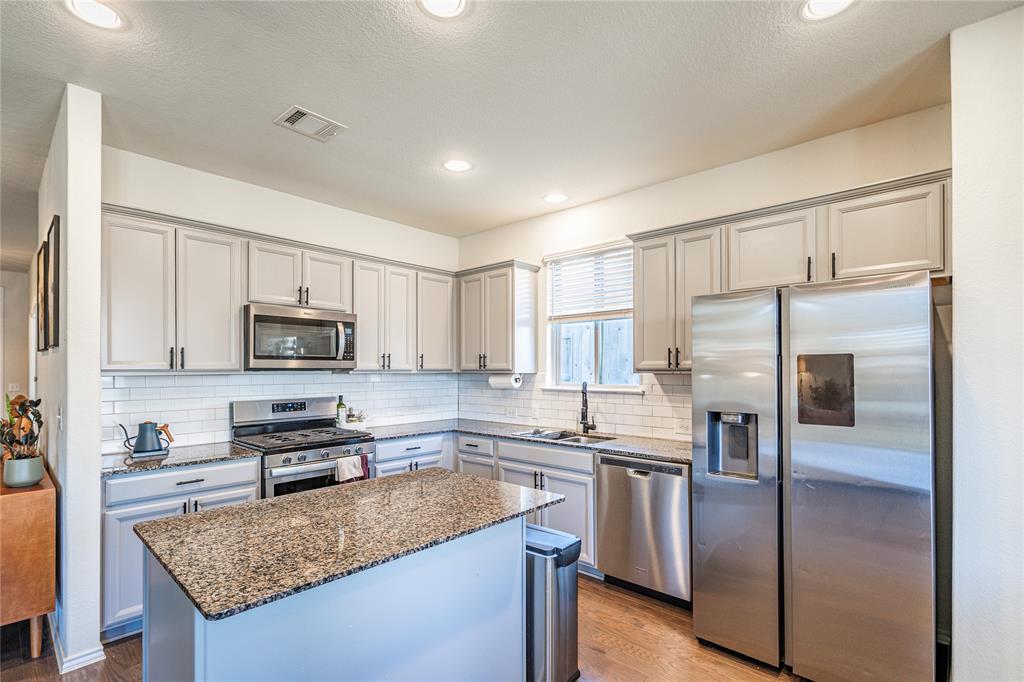 547 Saturnia Drive Georgetown, TX 78628 - Photo 15 of 39 a kitchen with stainless steel appliances granite countertop a refrigerator a stove a sink and a microwave