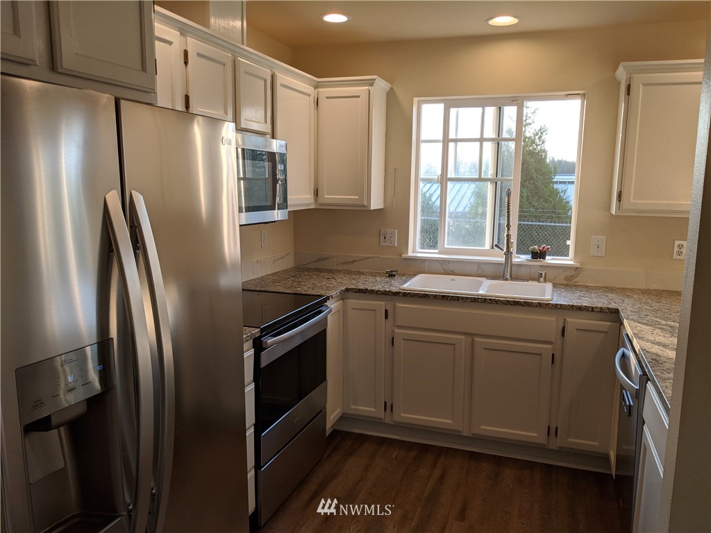 3224 Locust Avenue Bellingham, WA 98225 - Photo 5 of 28 a kitchen with stainless steel appliances a refrigerator sink and wooden cabinets