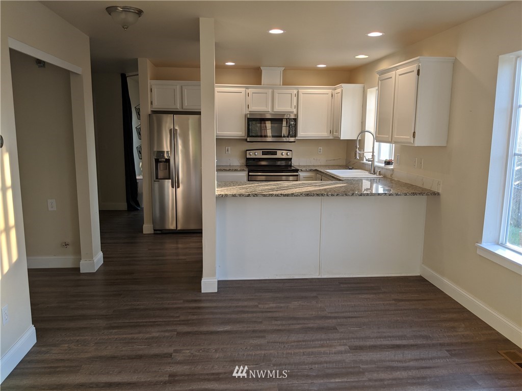 3224 Locust Avenue Bellingham, WA 98225 - Photo 9 of 28 a kitchen with stainless steel appliances granite countertop a refrigerator a stove and a sink with wooden floor