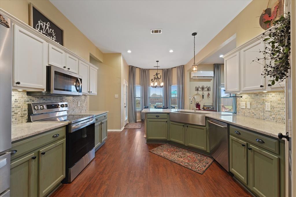 112 Springfield Lane Red Oak, TX 75165 - Photo 14 of 40 Spacious kitchen featuring two-tone cabinetry with white upper and olive green lower cabinets, wood-finish flooring, a stainless steel apron front sink, and light-colored, granite countertops with a mosaic tile backsplash