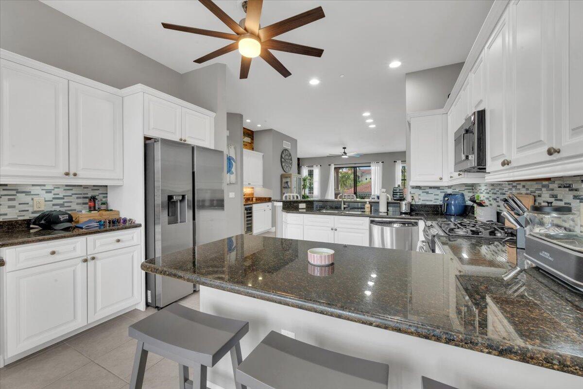 502 Del Sol Circle Tequesta, FL 33469 - Photo 15 of 73 a kitchen with stainless steel appliances granite countertop a refrigerator a stove and white cabinets with wooden floors