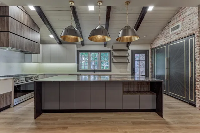 a kitchen with stainless steel appliances granite countertop a stove a sink dishwasher a refrigerator and a dining table with wooden floor