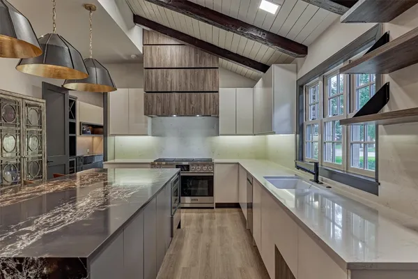 a kitchen with stainless steel appliances granite countertop a sink a stove and a wooden floors