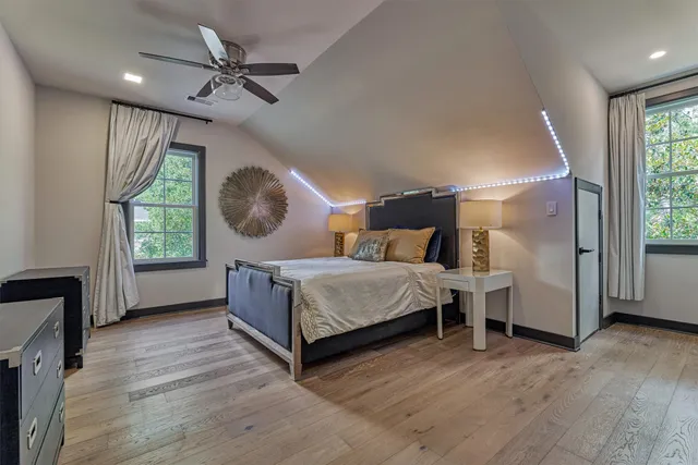 a bedroom with a bed a dresser and windows