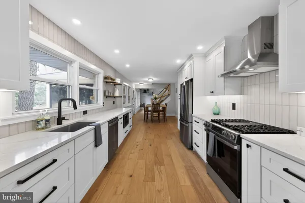 a large kitchen with stainless steel appliances a large counter top a stove a chimney a sink and a refrigerator