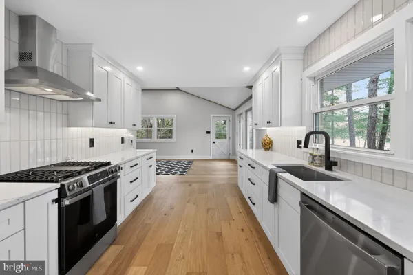 a large kitchen with stainless steel appliances granite countertop a lot of counter space and wooden floors