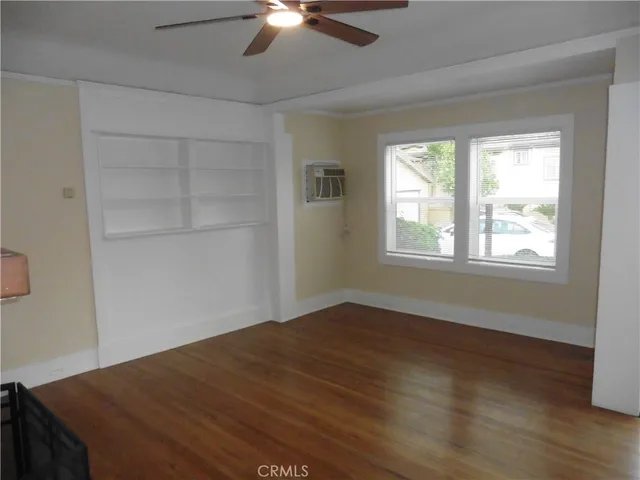 a view of an empty room with a window and wooden floor