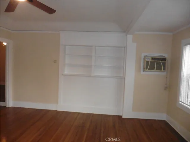 an empty room with wooden floor closet and windows