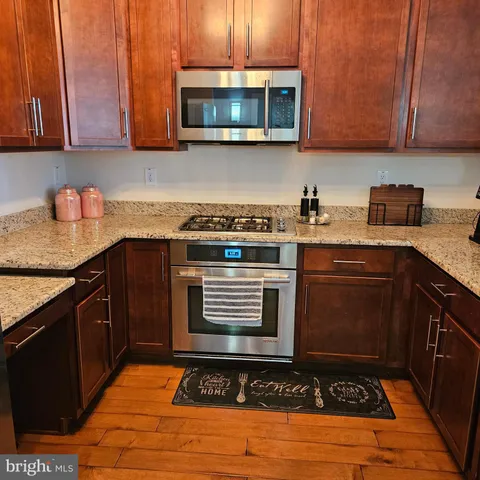 a kitchen with stainless steel appliances granite countertop a stove a sink and a microwave