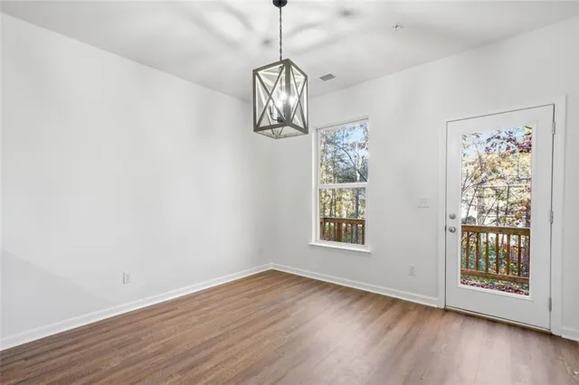 a view of a room with wooden floor chandelier and windows