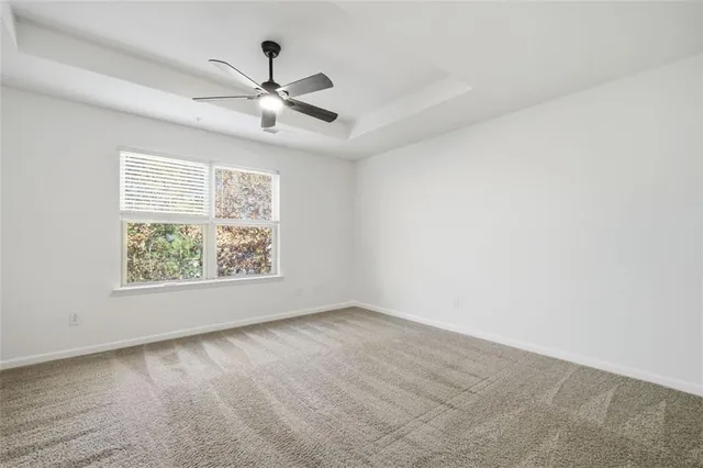 an empty room with windows and ceiling fan
