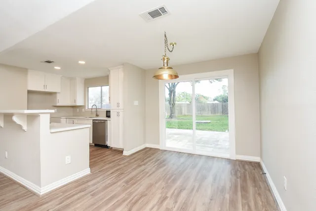 a open kitchen with white cabinets and wooden floor
