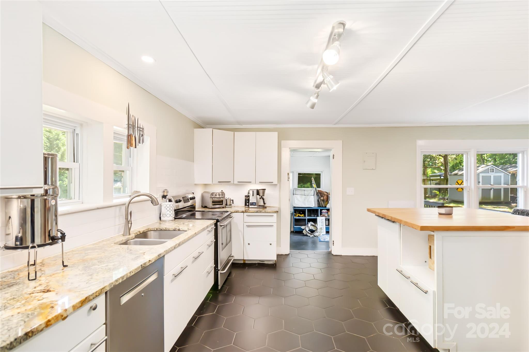 5500 Wilora Lake Road Charlotte, NC 28212 - Photo 13 of 32 a large white kitchen with a sink and dishwasher a stove top oven with wooden floor