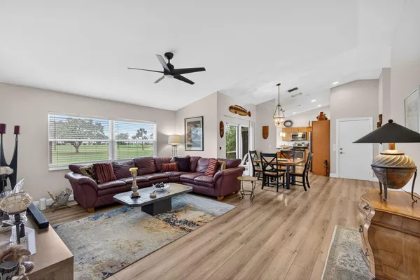 a living room with furniture floor to ceiling window hardwood floor and a flat screen tv