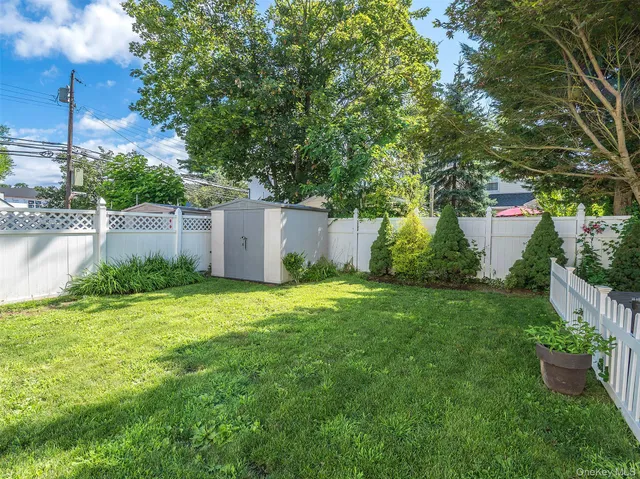 a backyard of a house with plants and large tree