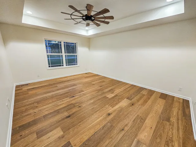 a view of empty room with wooden floor and fan