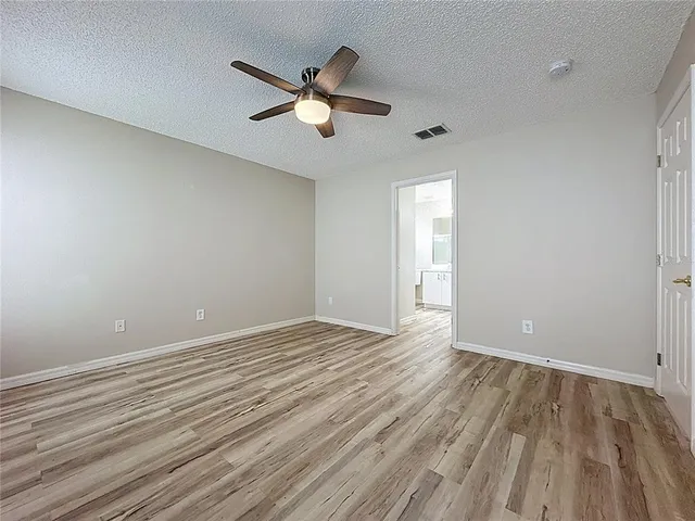 a view of an empty room with wooden floor and window