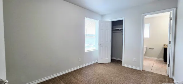 a view of an empty room with closet and a window