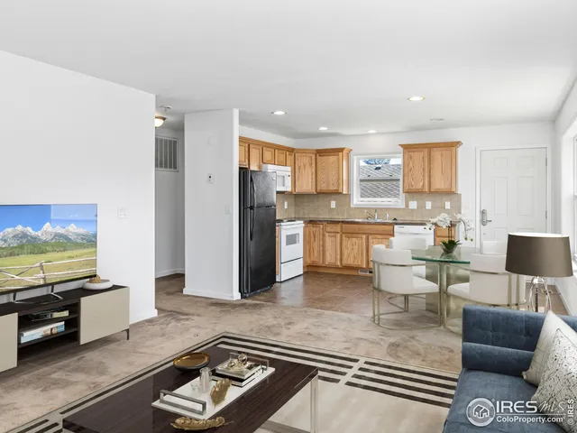 a living room with stainless steel appliances furniture a rug and a kitchen view