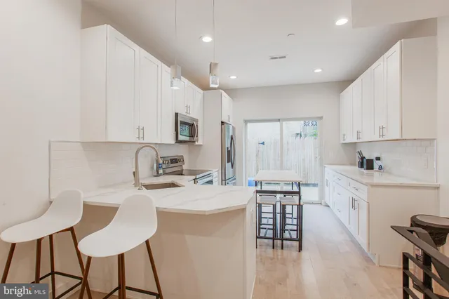 a kitchen with stainless steel appliances kitchen island granite countertop a stove a sink a refrigerator white cabinets and wooden floor