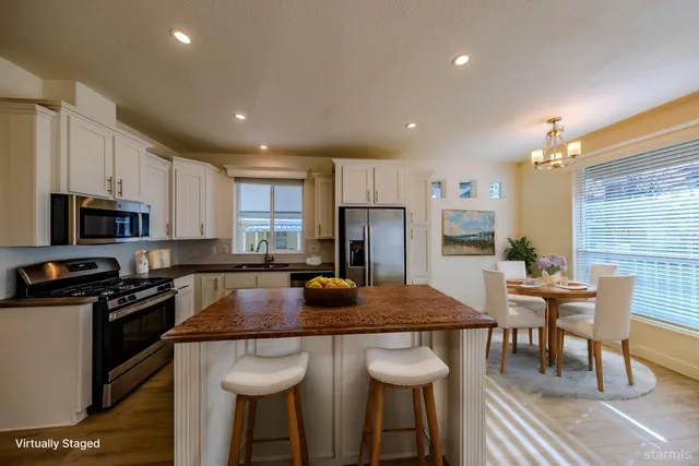 a kitchen with stainless steel appliances granite countertop a stove a sink a microwave a dining table and chairs