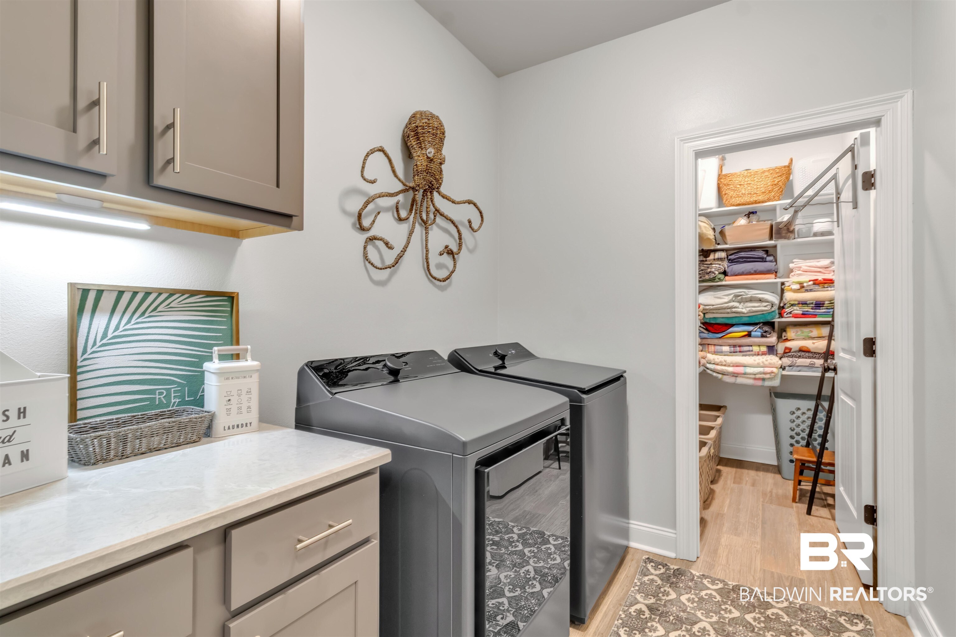 22531 Putter Lane Foley, AL 36535 - Photo 32 of 43 Laundry area featuring washing machine and clothes dryer, light wood finished floors, and cabinet space