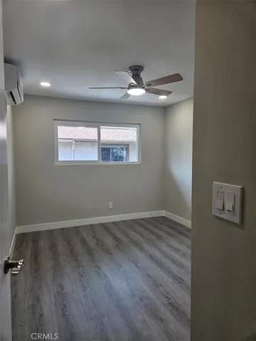 an empty room with wooden floor chandelier fan and windows